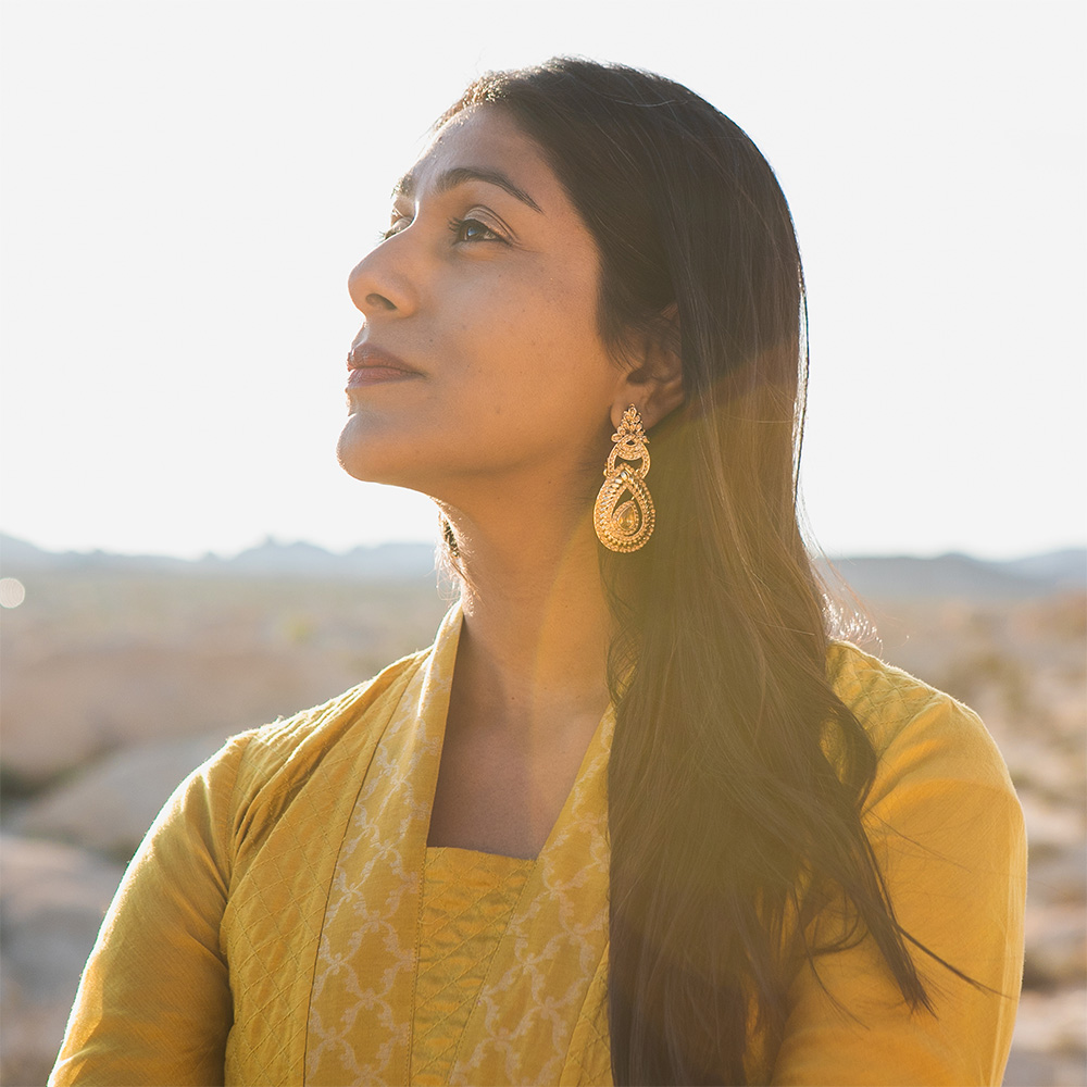 Portrait of Meena Srinivasan wearing a yellow dress and earrings